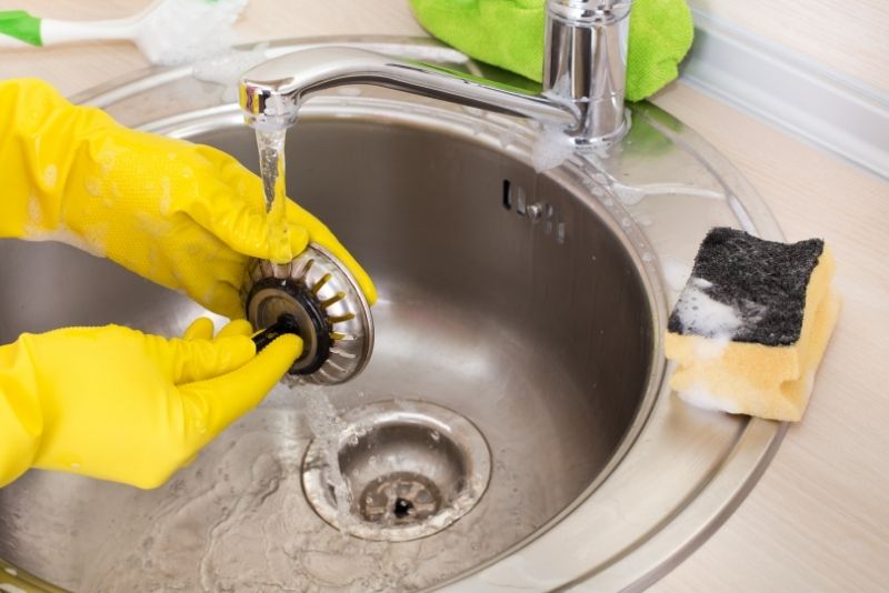 water flowing from a faucet in a sink with hands doing dishwashing cleaning
