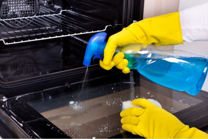 oven cleaning spraying the oven glass with soap