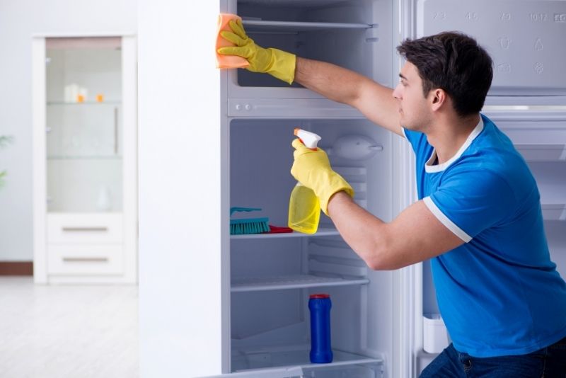 Gloved hands ready to clean a fridge